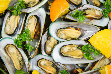锅中含有草药的罐壳和餐桌垫中含橙柠檬柑橘番茄的罐子蒸汽贝壳绿色为餐桌厅的海鲜食品提供了美味的海鲜食品图片