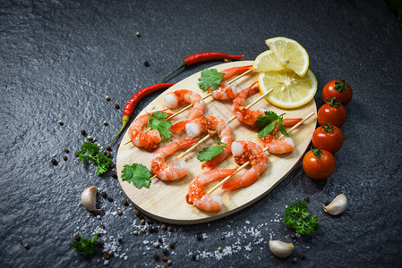 配虾的海产食品板和虾的海产食品配有辣酱药草和木制切割板背景的香料煮熟海产食品图片
