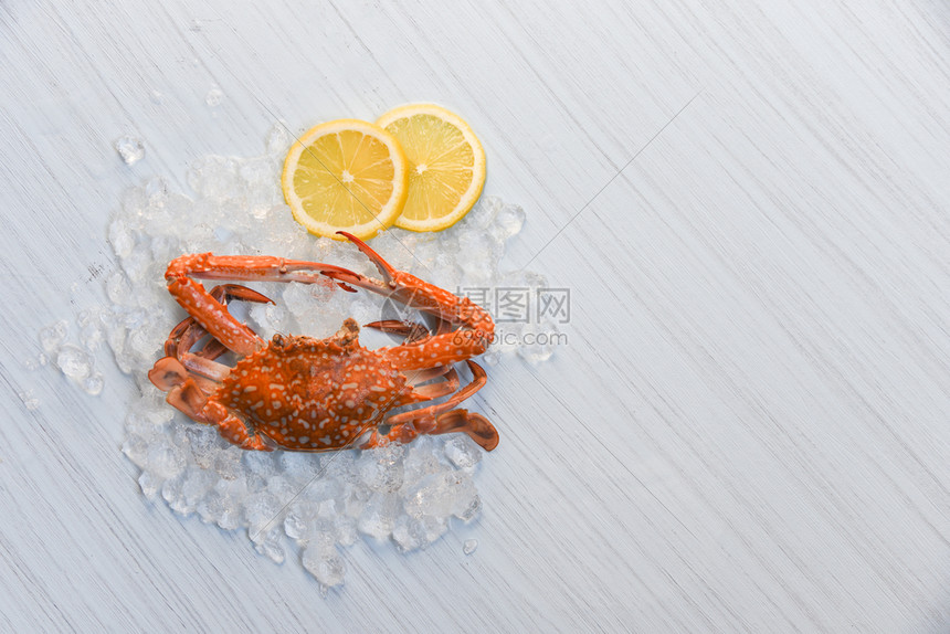 海食蟹蒸煮熟柠檬和白木本底的冰蓝游泳蟹图片