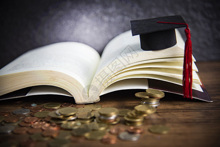 教育概念奖学金在黑底木上用硬币在一本公开书上以毕业限图片