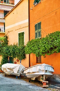 渔船停在意大利古里亚热那Boccadasse区多彩房屋旁边的街道上图片