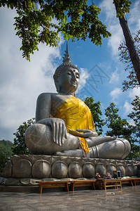 坐在岩石上有森林树和蓝天空背景的佛像图片