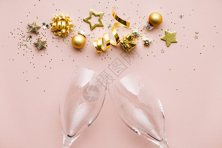 彩带星圣诞球彩蛋和香槟杯的金装饰粉红色背景平坦的躺下喜悦概念图片