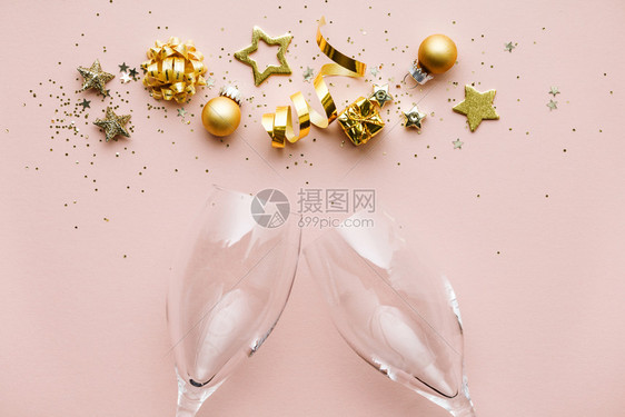 彩带星圣诞球彩蛋和香槟杯的金装饰粉红色背景平坦的躺下喜悦概念图片
