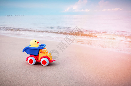 黄鸭玩具和彩色汽车在沙滩上孩子们节日快乐图片