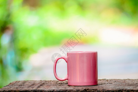 夏季自然绿色和黄背景的旧木材上陶瓷咖啡杯图片