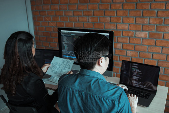 两名软件开发商正在使用计算机与其办公桌的合作伙伴图片