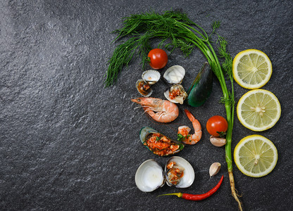 海产食品板和虾炒贝壳煮柠檬药草和暗底香料图片