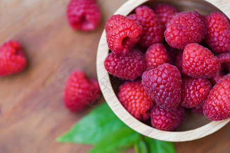 木碗中的新鲜树莓关闭红草莓果和绿叶顶视图背景图片