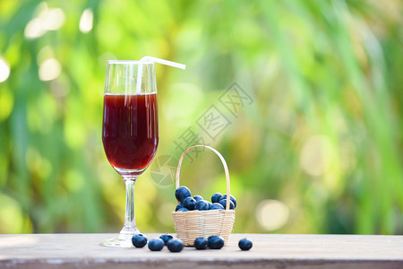 蓝莓果汁杯和新鲜蓝莓果子盛菜篮有大自然绿色夏季背景图片