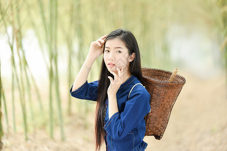 在天然竹林中皮肤美丽的亚洲妇女美丽的亚洲年轻女孩笑的肖像和农村收割业的篮子穿衣部落的生活图片