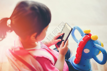 女孩手持电话玩智能手机在学校亚洲儿童23岁观看卡通图片