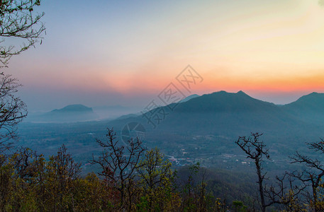清晨村的日出风景山其背为橙色和蓝的天空在山上带有树林前景的山上图片