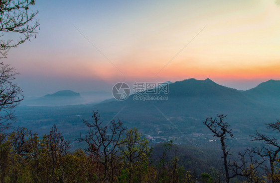 清晨村的日出风景山其背为橙色和蓝的天空在山上带有树林前景的山上图片