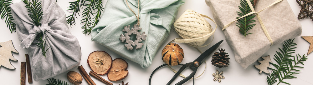 包装成的礼品和木制圣诞装饰可再使用的持续利生纺织礼品包装替代零废物概念平铺顶视图片