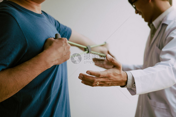 亚洲男理疗师的生治疗师在诊所工作帮助保护有病人在做伸展手术的病人在诊疗室用一个灵活的锻炼带进行伸展图片