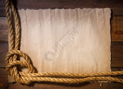 旧的纸板或木上的粗糙绳索被拖入海结中形成一个框架图片