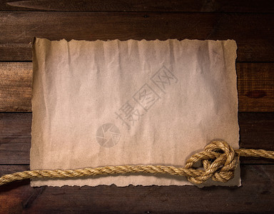 旧的纸板或木上的粗糙绳索被拖入海结中形成一个框架图片