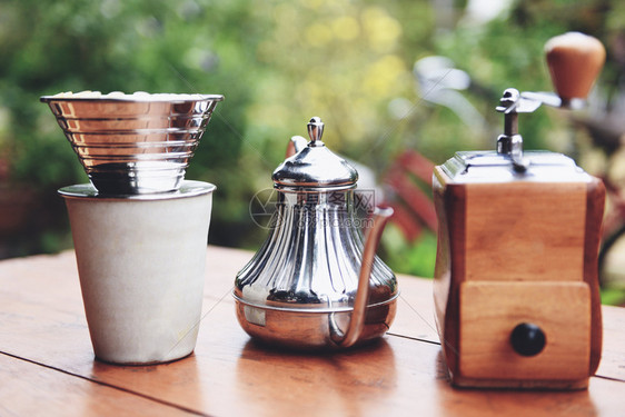 使杯子手在玻璃罐中滴水咖啡和木制桌边的研磨咖啡自然背景在过滤的酿酒中倒水Drip咖啡面包图片