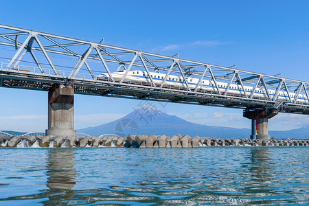 Shinkansen列车快速驾驶和经过东京火车站附近的藤田山在日本静冈富士河上架着钢桥图片