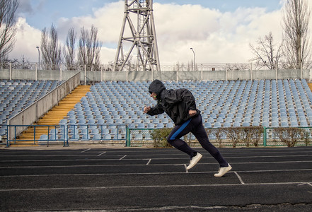 男子穿运动服去参加跑步通过一个空的体育场男子参加慢跑图片