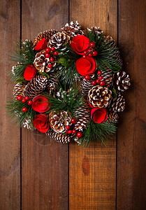 美丽的圣诞花圈挂在粗木质表面的纸花和卷毛枝图片