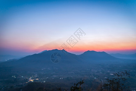 清晨村的日出风景山其背为橙色和蓝的天空在山上带有树林前景的山上图片