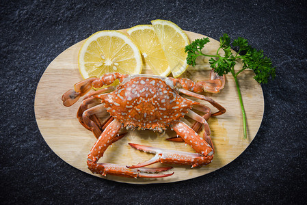 剪切板上用螃蟹煮的贝类海鲜底黑背景上配有草药和香料蒸汽蓝游泳蟹图片