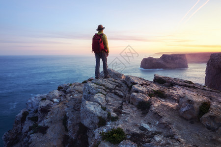 站在悬崖顶上有着振奋人心的海洋观独男背包者或徒步的后视图片
