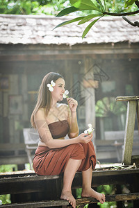 亚洲女泰籍戏剧风格服装和嗅闻鲜花美丽的年轻女孩肖像微笑泰国传统服装图片