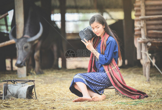 亚洲农业女民在村描绘美丽的年轻女孩快乐笑和听水牛农场旧收音机穿衣部落生活图片