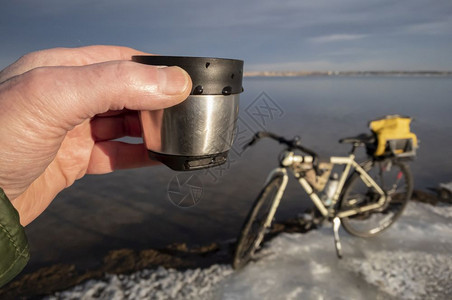 冬季骑自行车时在冰冷湖岸边的热茶杯科罗拉多北部的博伊德湖州立公园图片