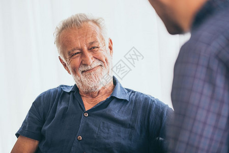 快乐的成年儿子和长父亲在家沙发上笑图片