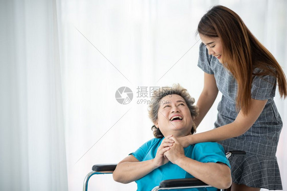 微笑和说话照顾者微笑在她的同时与老年妇女交谈图片
