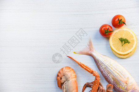 鱼虾和螃蟹爪海洋美食晚餐白桌背景的番茄柠檬图片