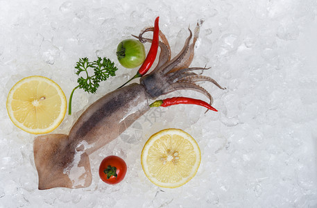 新鲜生鱿鱼海加柠檬面番茄和餐馆冰桶上的辣椒图片