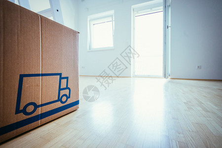 移动纸板盒在一个干净明亮的房间有木地板搬进新的家图片