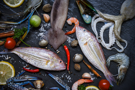 底黑含草菜和香料柠檬的新鲜海菜产食品板外壳虾蟹背景图片