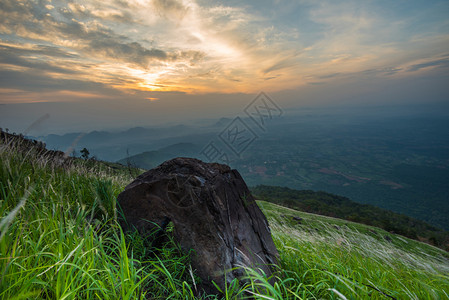 山上丘的风景日出绿地草原上石以及多彩的天空背景太阳在清晨升起图片