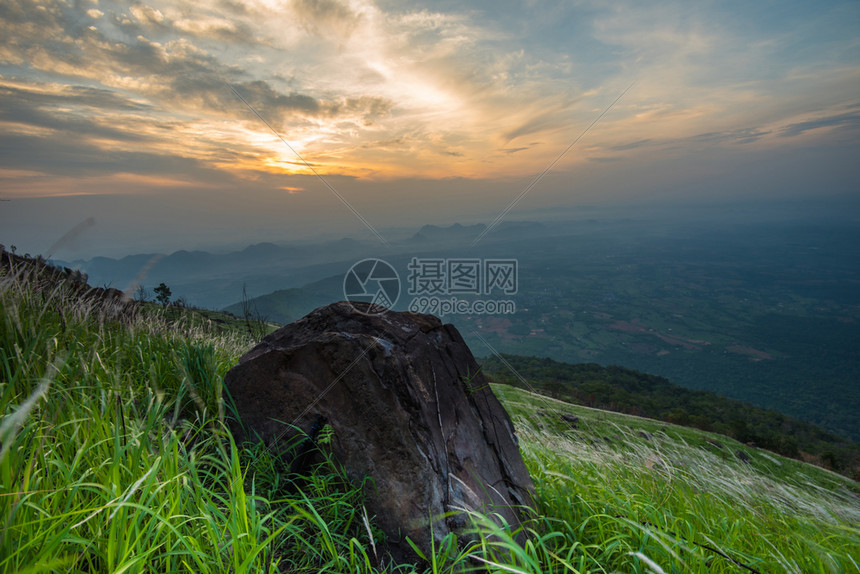 山上丘的风景日出绿地草原上石以及多彩的天空背景太阳在清晨升起图片