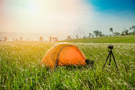 山丘的帐篷地区山丘日出风景露营帐篷黄在森林的田野上与数字相机在早晨美丽的天然绿草地图片