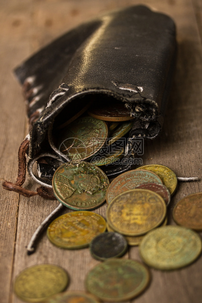 不同的旧黑皮革钱袋和小铜硬币放在旁边的粗木制桌上硬币图片