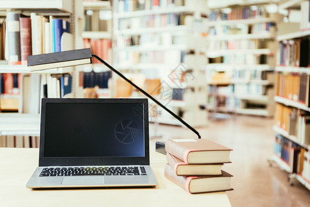 笔记本电脑和木制桌子上的一堆书大学图馆图片