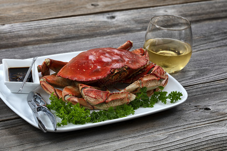 晚餐桌里整个煮熟的邓吉内斯螃蟹配着白葡萄酒贴近布局图片