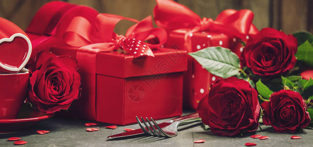 情人节概念木制背景的红弓礼物带有色的丝弓情人节礼物盒与红色的丝带弓捆绑在一起以及生锈背景的美丽玫瑰情人节概念带有红色的丝弓情人节图片
