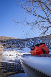 起立在甲板上挂着干袋的桨板上在山湖进行冬季风景在动摄像机上拍POV图片