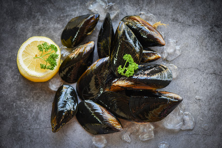 含有草药柠檬和黑板底新鲜海贝壳鱼在餐馆的冰上或市场销售的贝壳食品图片