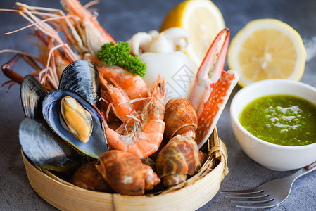 盘面黑石背景的比伦贝壳螃蟹和海鲜酱柠檬烹饪蒸汽食品为海鲜自助餐提供的概念图片