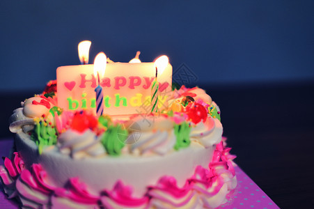 生日蛋糕多彩晚上桌有蜡烛灯亮贴着生日快乐的标签图片