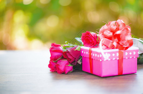 情人节礼物盒花爱概念粉红礼物盒带丝弓红玫瑰的花木桌绿色背景图片